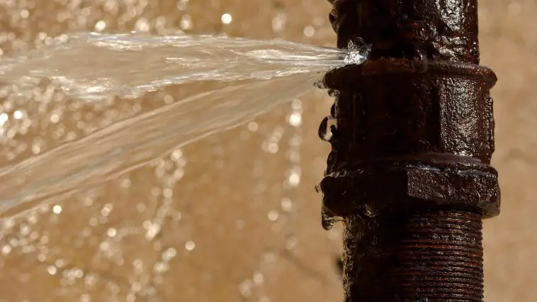 Rusty burst pipe squirting water at high pressure