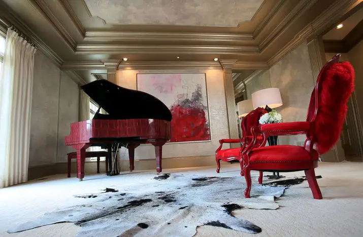 Room with a piano and red chairs